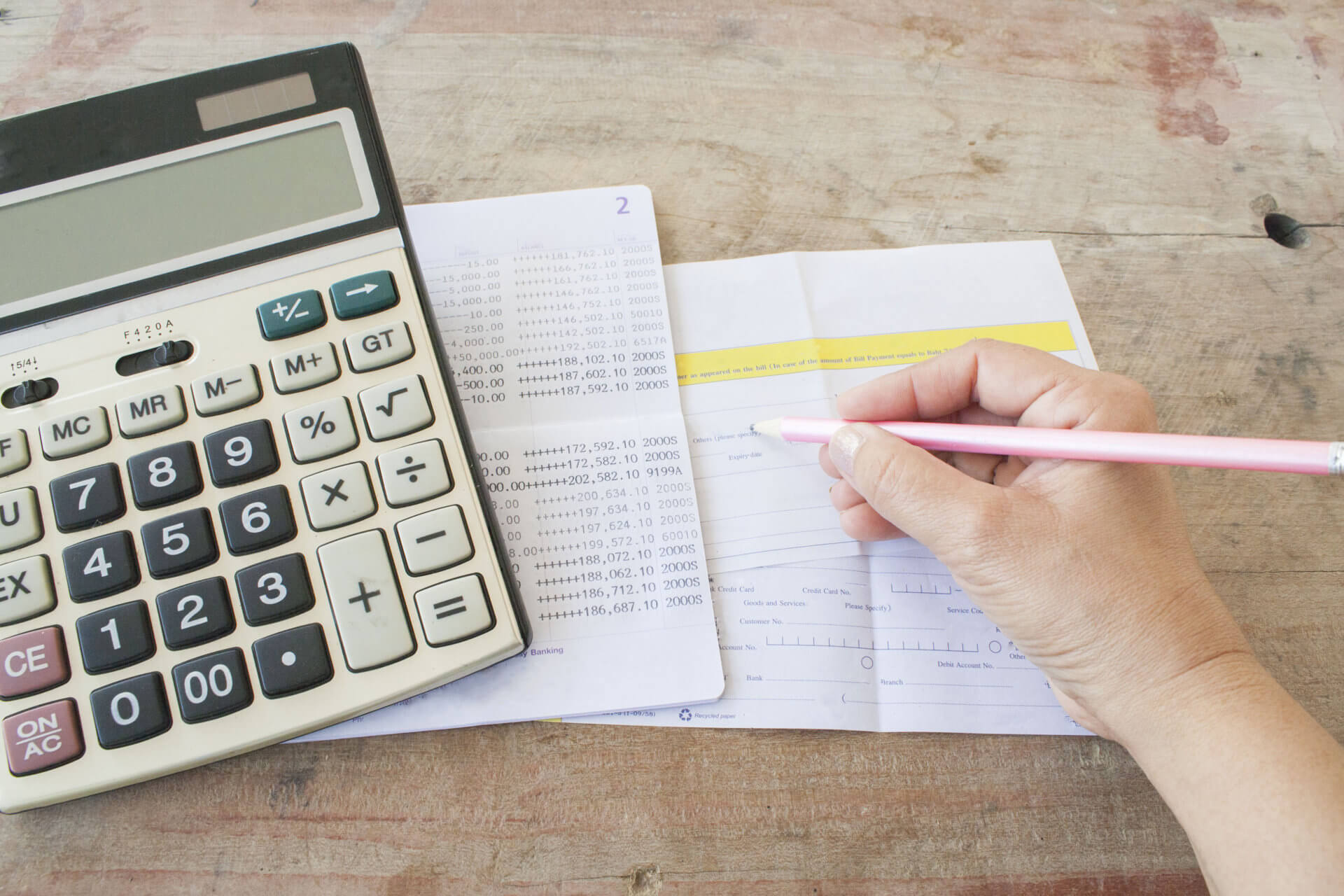 photo d'une main d'une personne faisant des calculs avec un stylo et une calculatrice