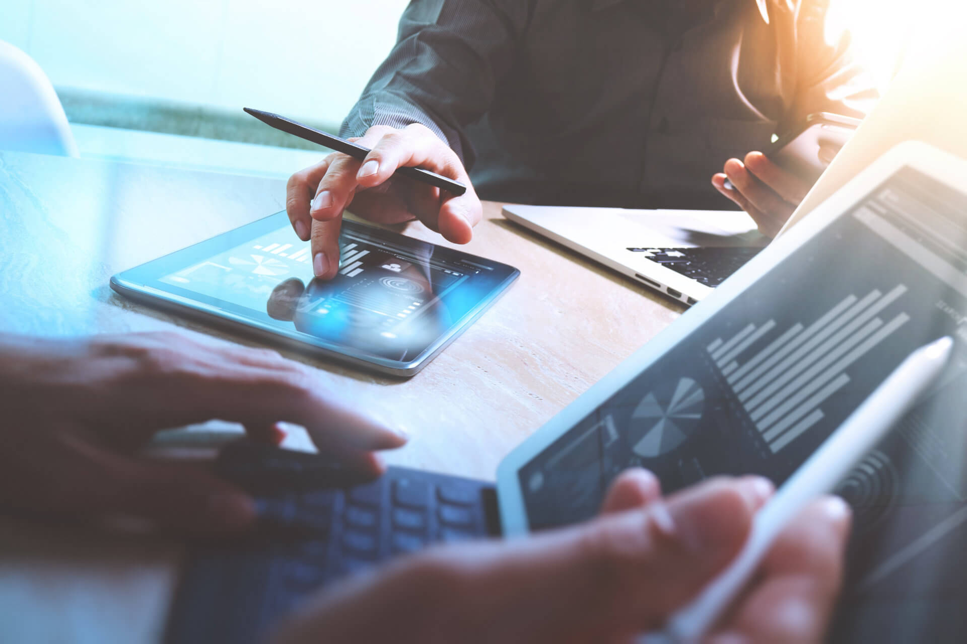 collaborateurs travaillant sur tablettes et ordinateurs avec des graphiques financiers